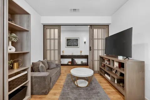 a living room with furniture a flat screen tv and a floor to ceiling window