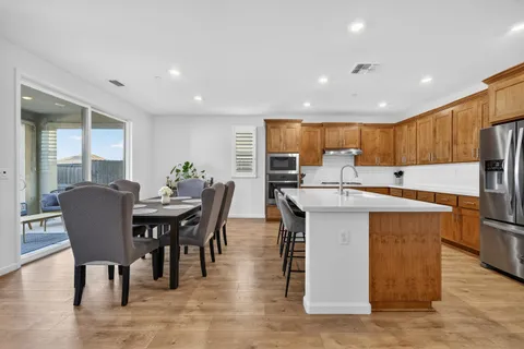 a kitchen with stainless steel appliances granite countertop a table chairs sink refrigerator and cabinets