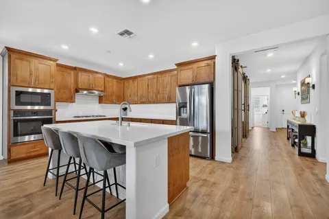 a kitchen with stainless steel appliances a table chairs refrigerator and a sink