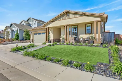 a front view of a house with a yard and potted plants