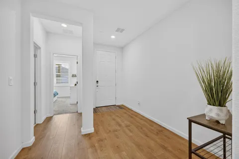 a view of a hallway with wooden floor and a bathroom