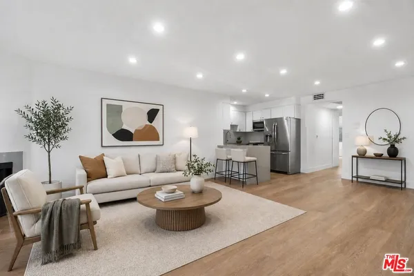 a living room with furniture a refrigerator and a potted plant
