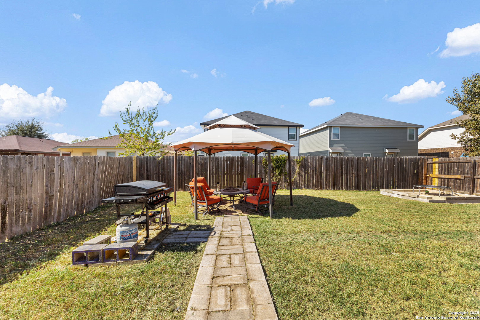 3819 Bacall Way Converse, TX 78109 - Photo 17 of 19 a view of a backyard with table and chairs under an umbrella with wooden fence