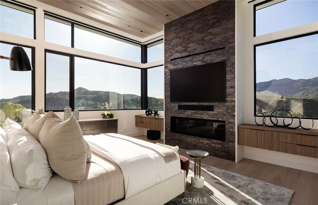 12530 Stagecoach Road Malibu, CA 90265 - Photo 15 of 45 a bedroom with a bed a flat screen tv and a fireplace