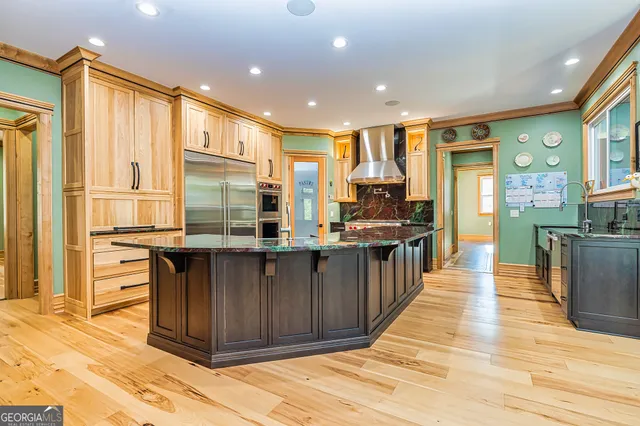 a kitchen with stainless steel appliances granite countertop a refrigerator a sink dishwasher and wooden cabinets with wooden floor