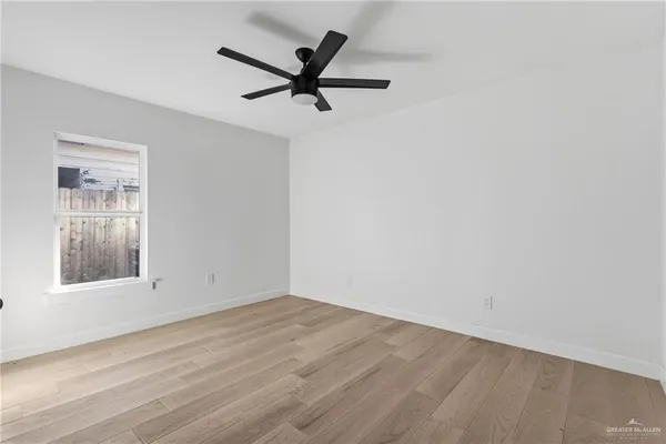 an empty room with a window and a view of a ceiling fan