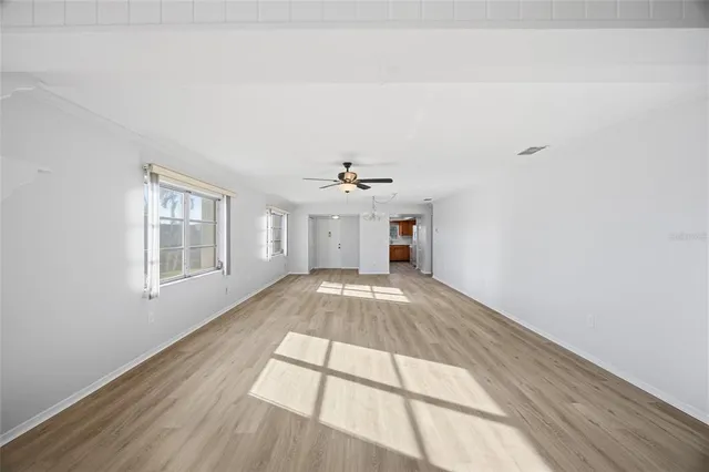 a view of an empty room with chandelier and wooden floor