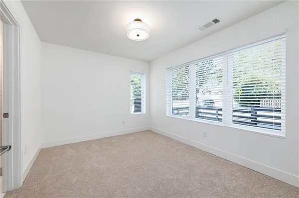 an empty room with wooden floor fireplace and windows