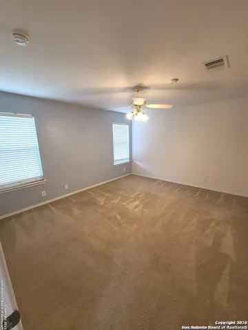 en empty room with windows and ceiling fan