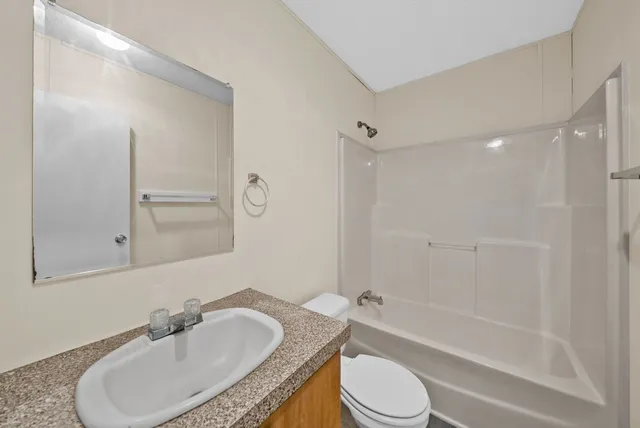 a bathroom with a granite countertop sink toilet a mirror and shower