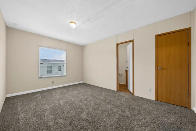a view of an empty room with closet and a window