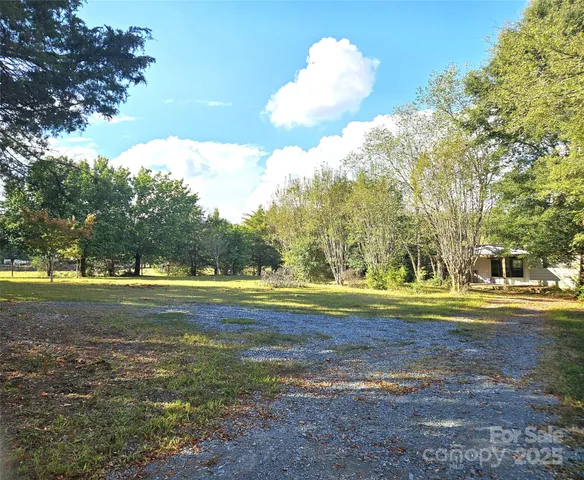 a view of a fountain in a yard with large trees