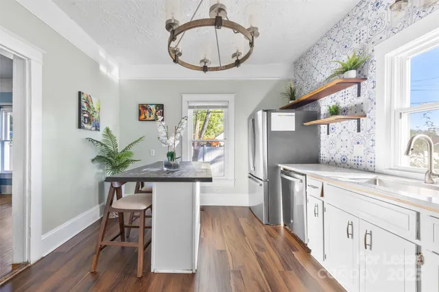 a kitchen with stainless steel appliances a table chairs refrigerator and cabinets