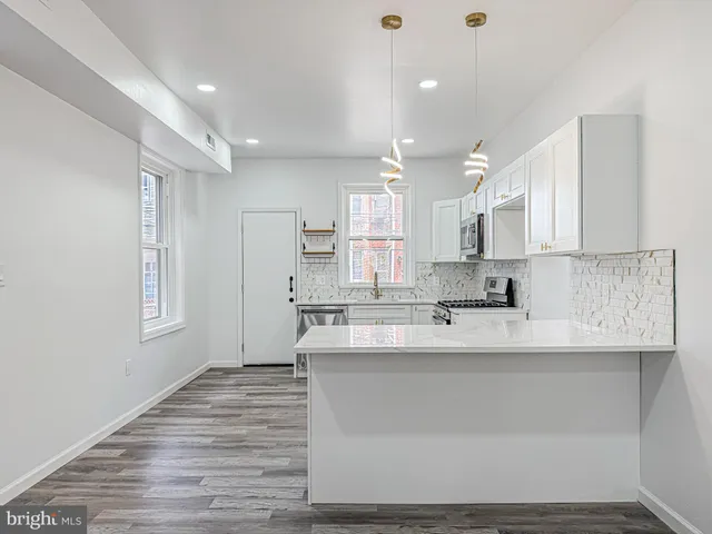 a large white kitchen with kitchen island a sink stainless steel appliances and cabinets