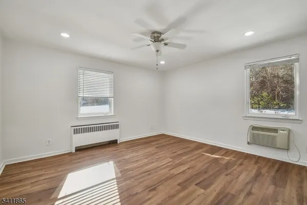 an empty room with wooden floor fan and windows