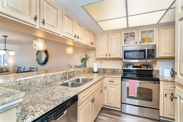 a kitchen with granite countertop a sink stainless steel appliances and cabinets