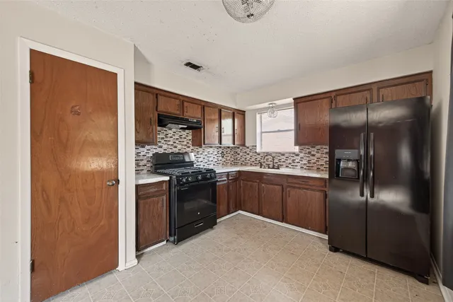 a kitchen with stainless steel appliances granite countertop a refrigerator and a stove top oven