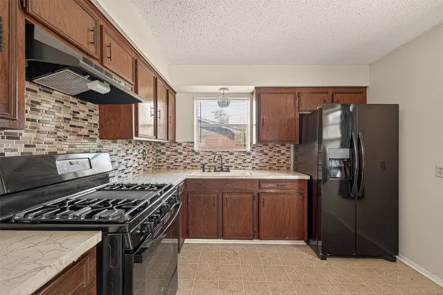 a kitchen with stainless steel appliances granite countertop a stove a refrigerator and a sink