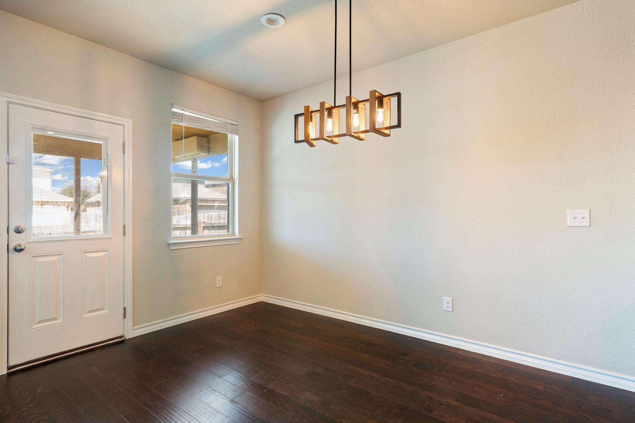 1341 Eagle Ray Street Leander, TX 78641 - Photo 8 of 37 Rich hardwood floors complement an elegant chandelier in this well-appointed dining space.