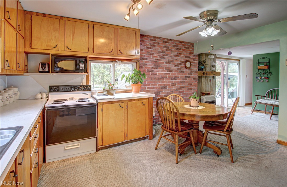 3946 Poe Road Medina, OH 44256 - Photo 5 of 35 Kitchen featuring white range with electric stovetop, brown cabinets, brick wall, light countertops, light carpet, plenty of natural light, and ceiling fan