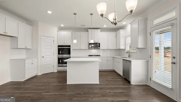 a kitchen with stainless steel appliances granite countertop a stove a sink and white cabinets with wooden floors