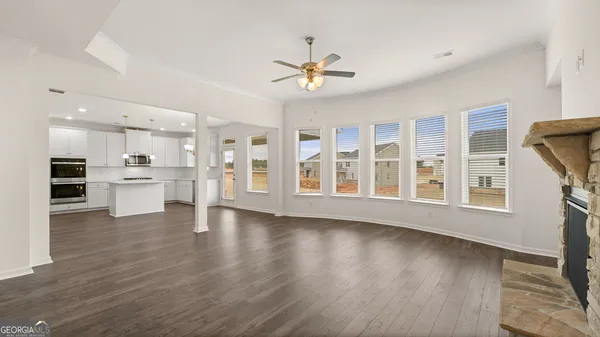 a view of an empty room with wooden floor and a kitchen