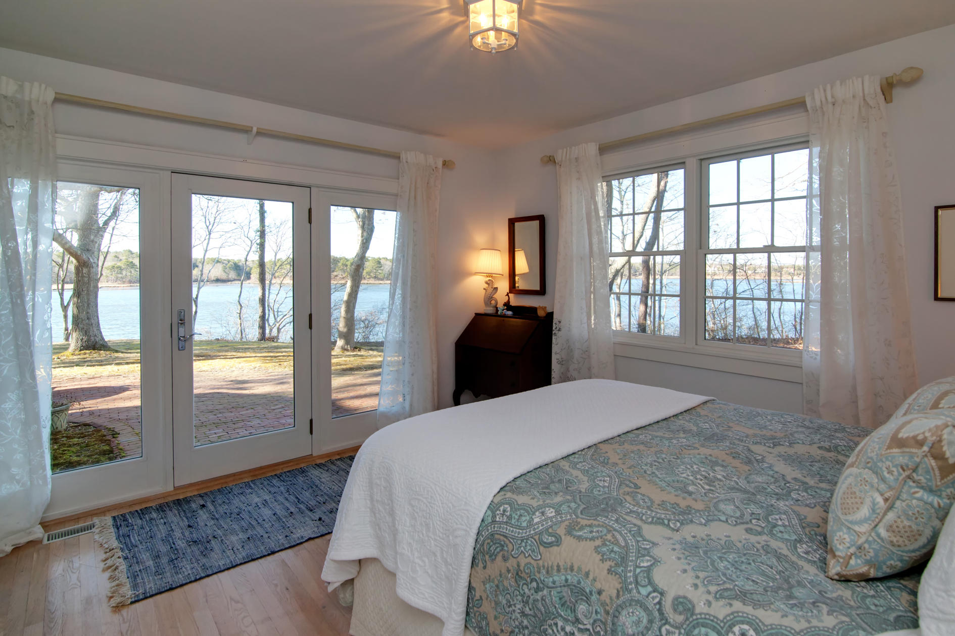 624 Poponessett Road Cotuit, MA 02635 - Photo 24 of 30 a bedroom with a large bed and a chandelier next to a window