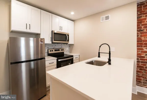 a kitchen with refrigerator a microwave a sink and cabinets