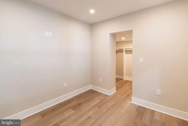 a view of an empty room with wooden floor and closet
