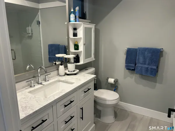 a bathroom with a granite countertop sink a large mirror and a toilet