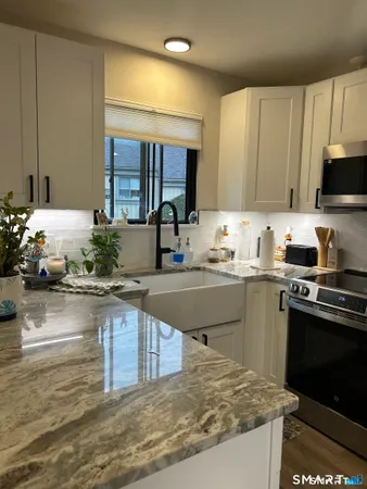 a kitchen with kitchen island granite countertop a sink cabinets and stainless steel appliances