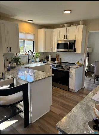 a kitchen with stainless steel appliances granite countertop a sink a stove a refrigerator and cabinets
