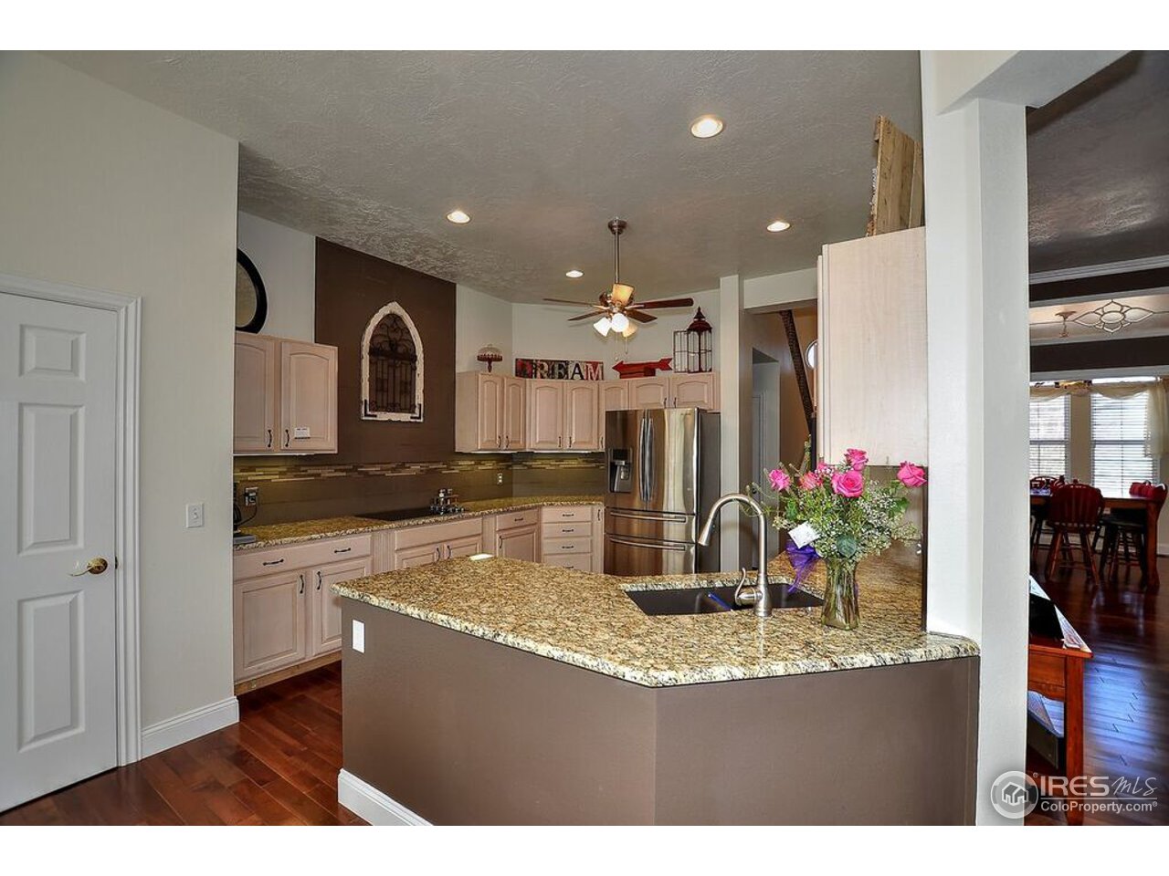 126 52nd Avenue Greeley, CO 80634 - Photo 6 of 24 a kitchen with kitchen island granite countertop a sink cabinets and wooden floor