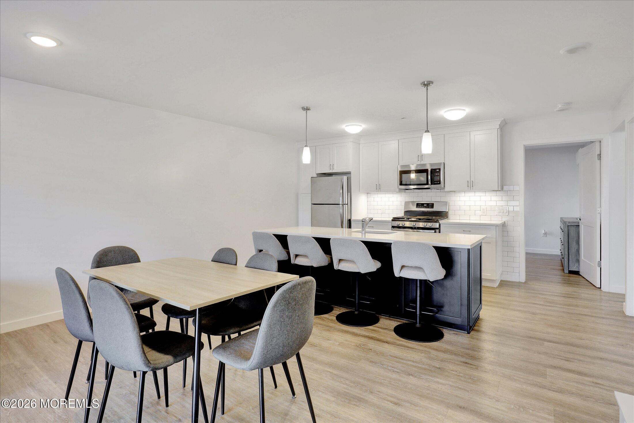 55 Brighton Avenue, Unit 4 Long Branch, NJ 07740 - Photo 12 of 36 a open kitchen with stainless steel appliances kitchen island granite countertop a dining table chairs and a refrigerator