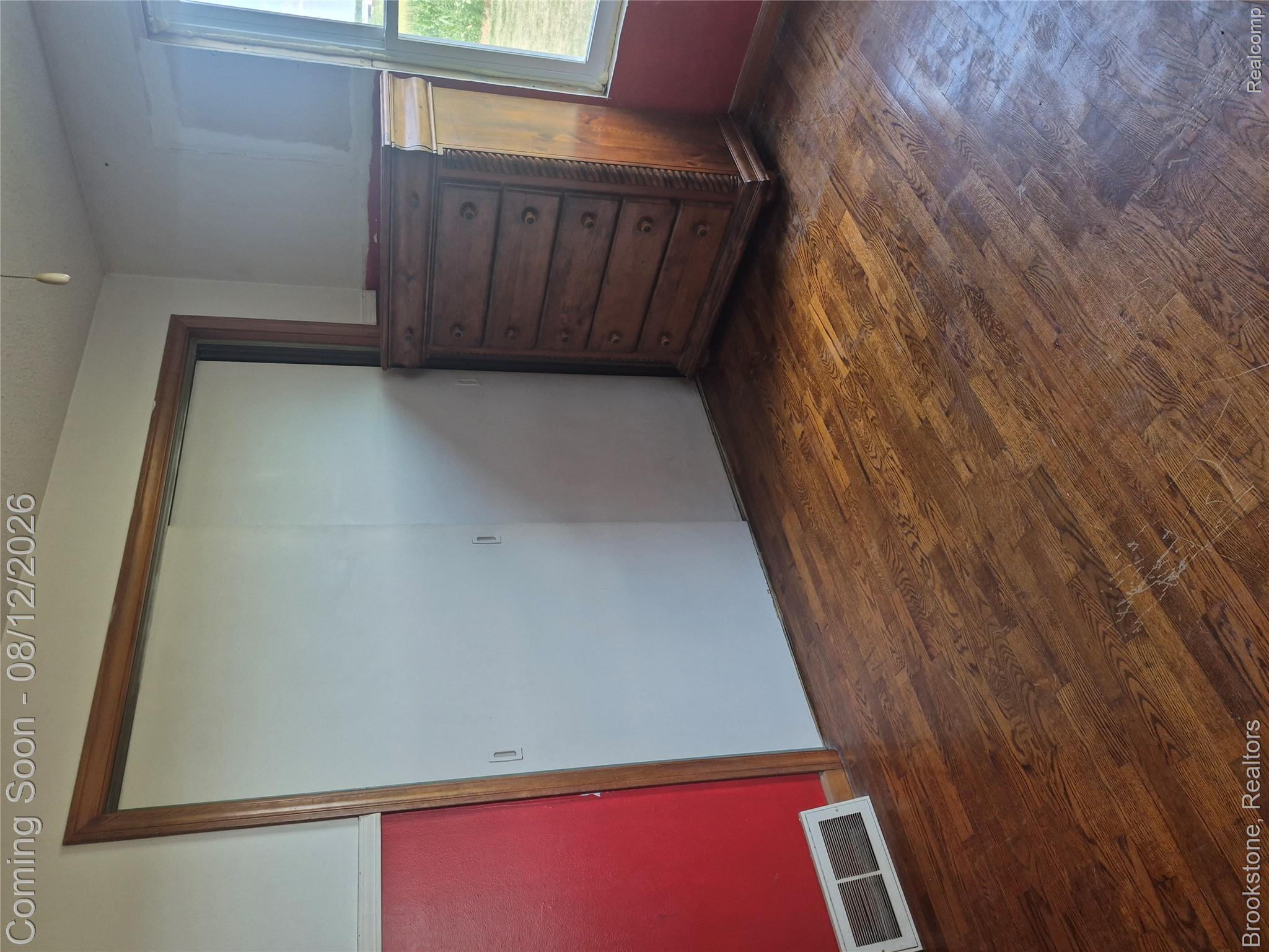 8426 Lake Pleasant Road Clifford, MI 48727 - Photo 14 of 33 Spacious bedroom featuring rich wood-finish flooring, a large sliding door closet with wood frame, and wooden dresser