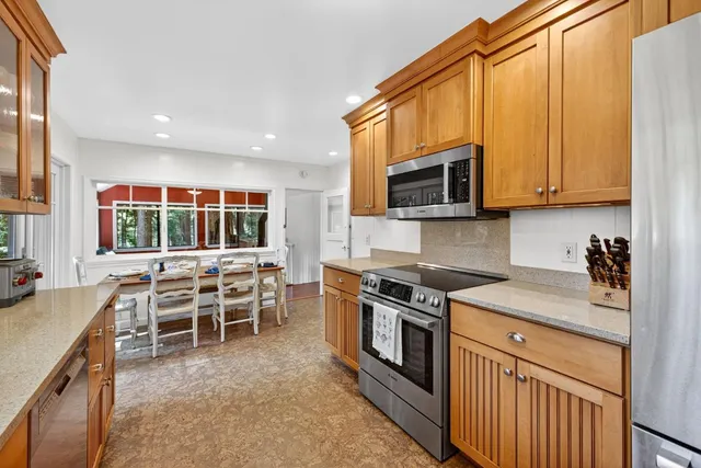 a kitchen with stainless steel appliances granite countertop a stove top oven a sink a microwave and a dining table