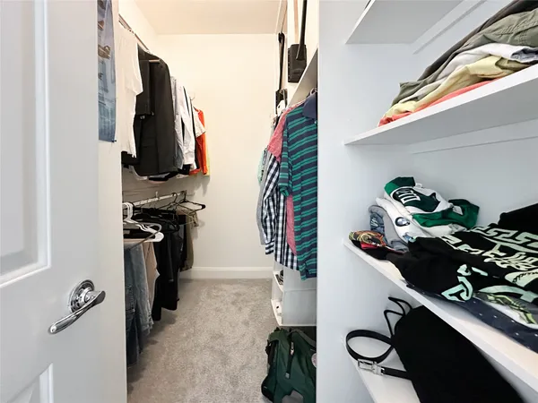 a view of walk in closet with clothes and shoes