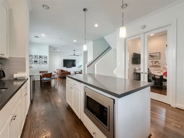 a kitchen with granite countertop a stove a sink a kitchen island with wooden floor and cabinets