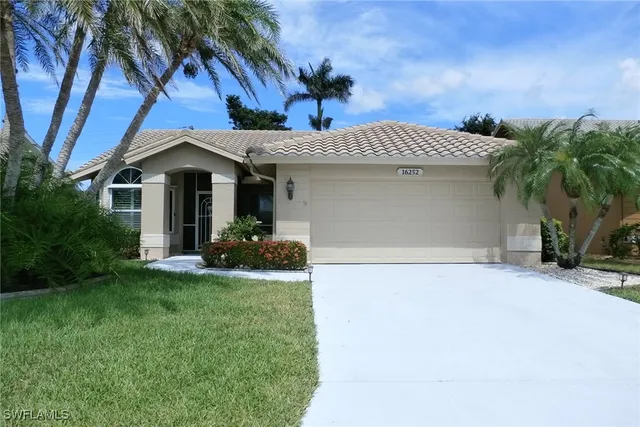 a view of a white house with a small yard and a large tree