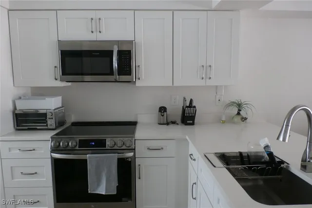 a kitchen with stainless steel appliances a stove a microwave a sink and cabinets
