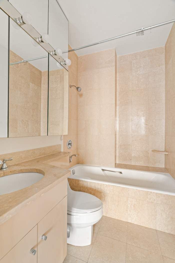 200-210 East 65th Street, Unit 30E Manhattan, NY 10065 - Photo 14 of 17 a bathroom with a sink a toilet and a bathtub
