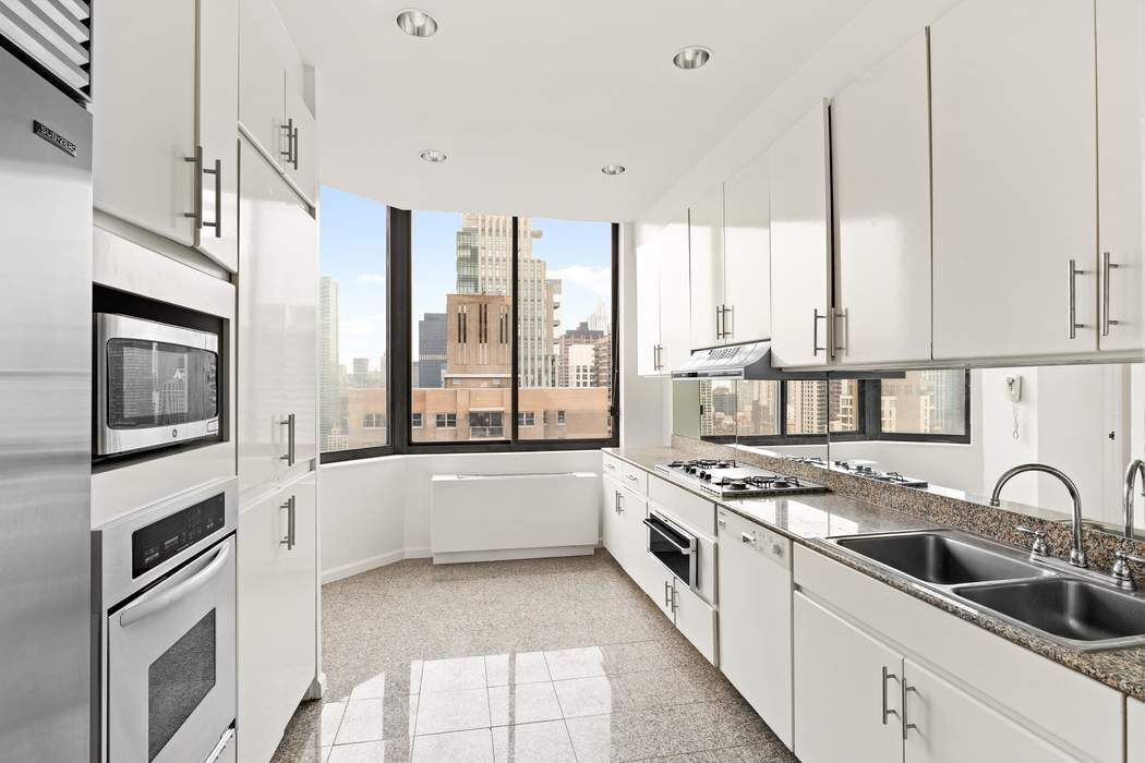 200-210 East 65th Street, Unit 30E Manhattan, NY 10065 - Photo 8 of 17 a large kitchen with stainless steel appliances granite countertop a stove a sink and a granite counter tops
