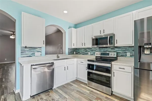 a kitchen with kitchen island granite countertop a stove top oven a sink and dishwasher with wooden floor