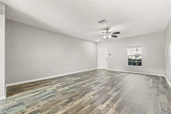 wooden floor in an empty room with a chandelier fan