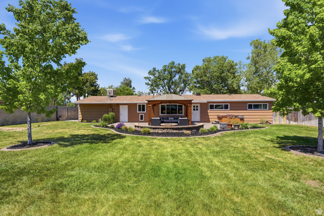6889 South Village Road Salt Lake City, UT 84121 - Photo 32 of 44 Spacious backyard featuring a large lawn, mature trees, and a stone-paver patio