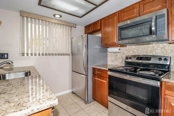 a kitchen with granite countertop cabinets stove top oven and microwave
