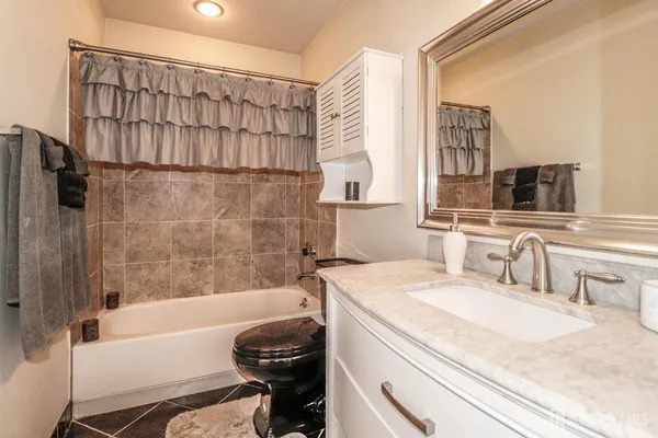 a bathroom with a granite countertop shower a sink and a mirror