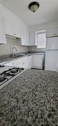 a kitchen with granite countertop white cabinets and white appliances