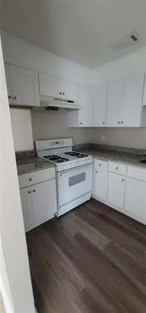 a kitchen with granite countertop white cabinets and white appliances