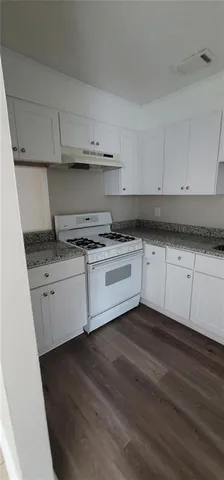 a kitchen with granite countertop white cabinets and white appliances